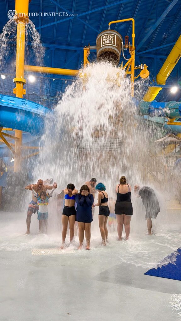 Family with three tween daughters enjoys the Great Wolf Lodge Naples water park together under the bucket drop waterfall 